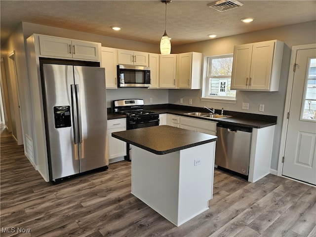 kitchen featuring pendant lighting, sink, stainless steel appliances, and dark wood-type flooring