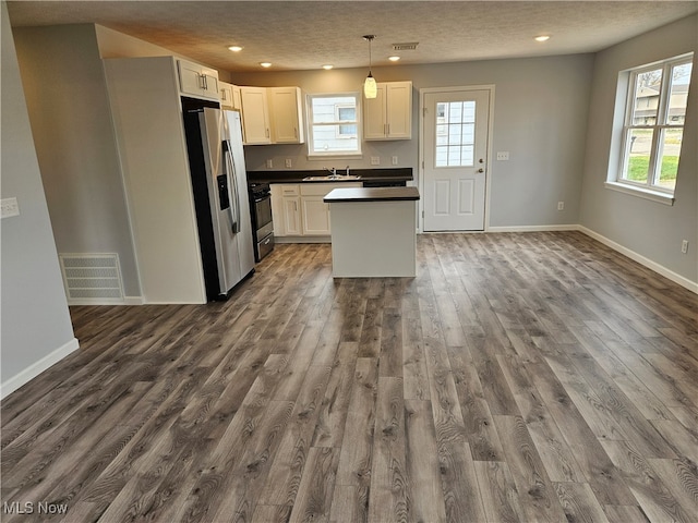 kitchen featuring decorative light fixtures, white cabinetry, stainless steel appliances, and plenty of natural light