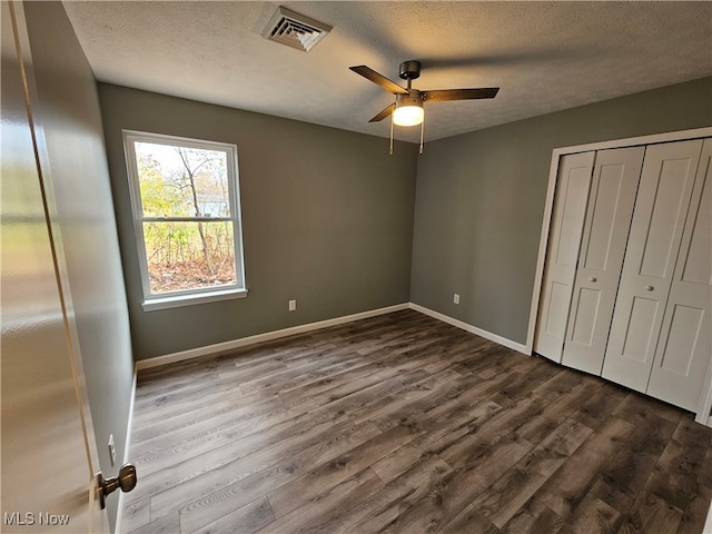 unfurnished bedroom featuring ceiling fan, dark hardwood / wood-style flooring, and a textured ceiling