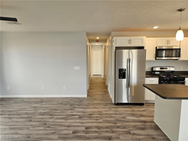 kitchen with decorative light fixtures, stainless steel appliances, white cabinetry, and dark hardwood / wood-style floors