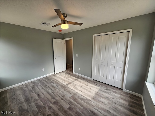 unfurnished bedroom with a textured ceiling, ceiling fan, light hardwood / wood-style flooring, and a closet