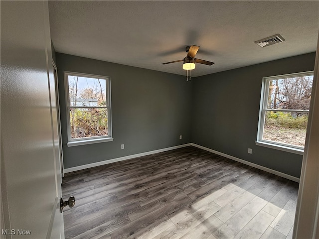 spare room featuring ceiling fan, plenty of natural light, wood-type flooring, and a textured ceiling