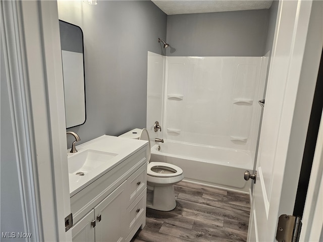 full bathroom featuring vanity, wood-type flooring, toilet, a textured ceiling, and shower / bath combination