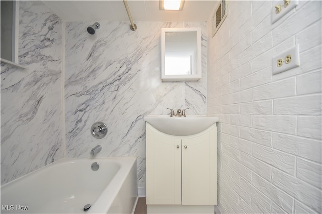 bathroom with tile walls, shower / washtub combination, and vanity