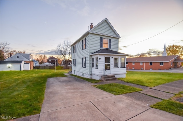 view of front of home with a garage, an outbuilding, and a lawn