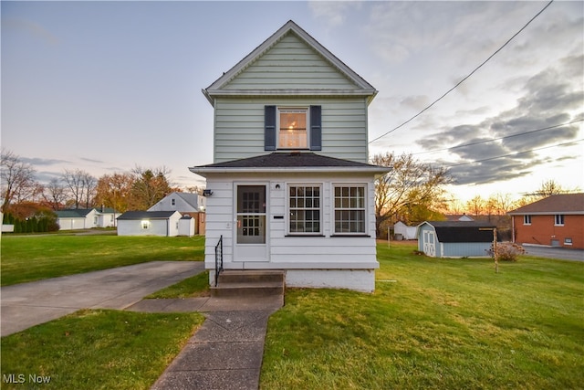 view of front of home with a storage shed and a lawn