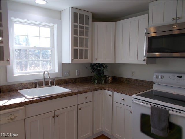 kitchen with white cabinetry, a wealth of natural light, sink, and white appliances