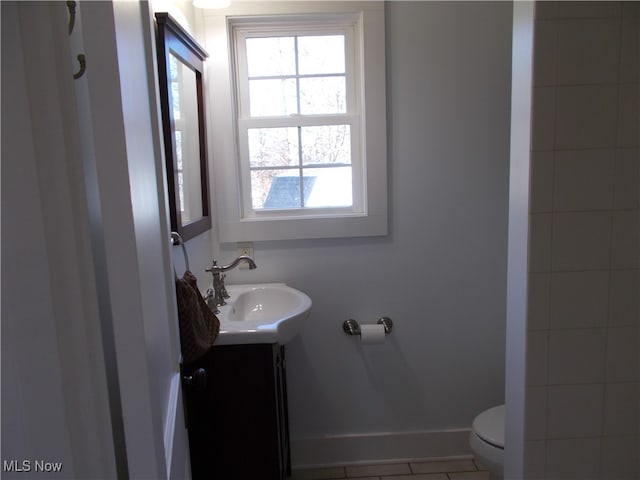 bathroom with toilet, vanity, a wealth of natural light, and tile patterned floors