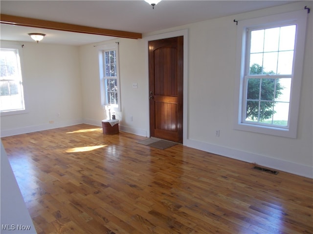 spare room with dark hardwood / wood-style flooring and beam ceiling