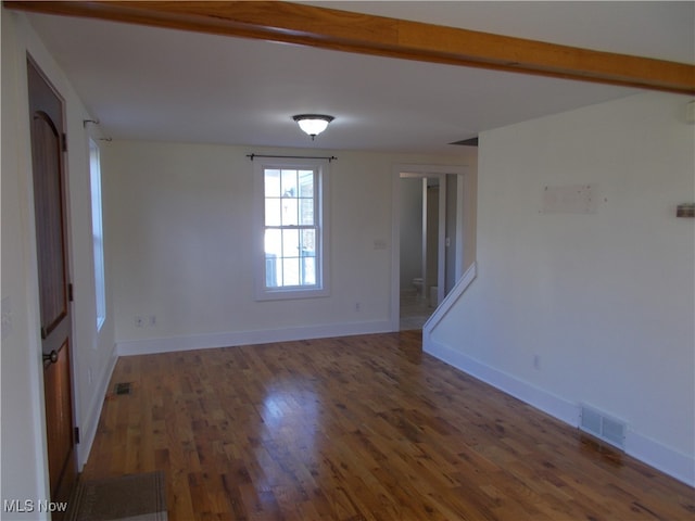 unfurnished room with beamed ceiling and dark hardwood / wood-style floors