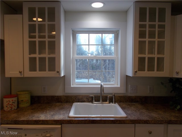 kitchen with sink, washer / dryer, and white cabinets