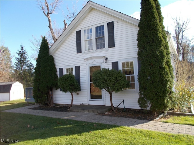 view of front of property with a front lawn and a shed