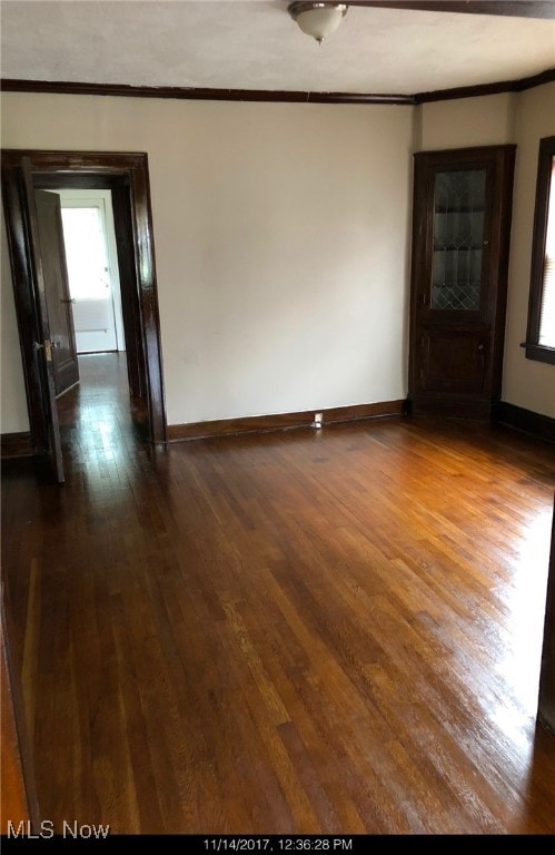 unfurnished room with dark hardwood / wood-style floors and crown molding