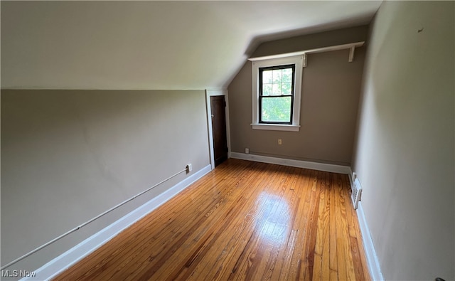 additional living space featuring light wood-type flooring and vaulted ceiling