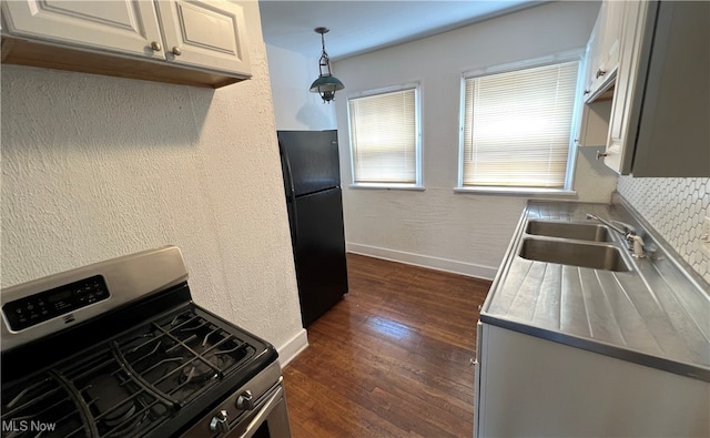 kitchen with stainless steel range with gas cooktop, black fridge, sink, dark hardwood / wood-style floors, and decorative light fixtures