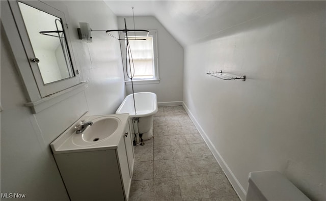 bathroom with vanity, a washtub, and lofted ceiling