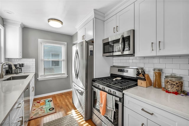 kitchen with decorative backsplash, stainless steel appliances, sink, light hardwood / wood-style flooring, and white cabinetry