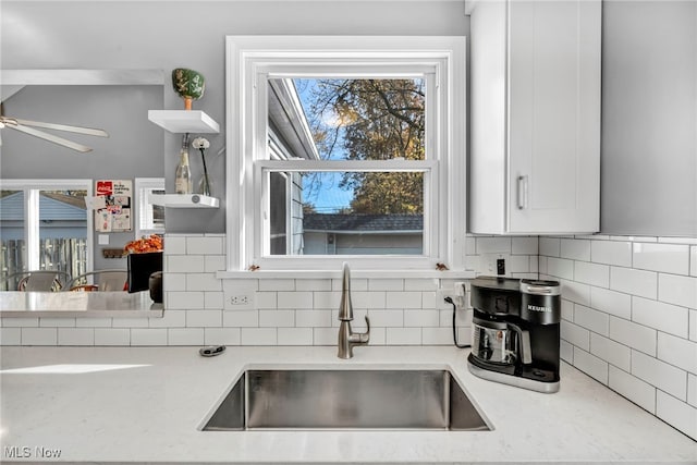 kitchen with sink, ceiling fan, light stone countertops, tasteful backsplash, and white cabinetry