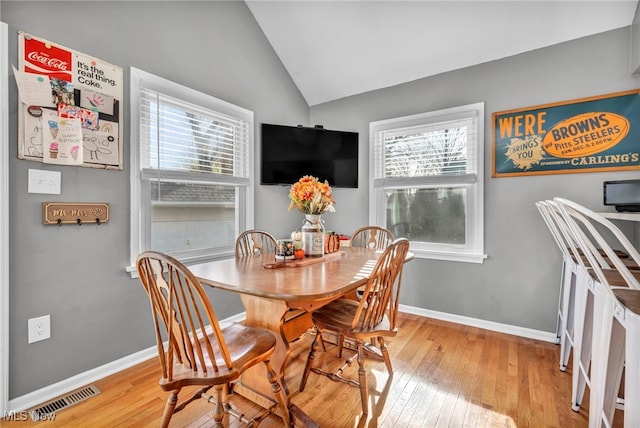 dining area with a healthy amount of sunlight, vaulted ceiling, and light hardwood / wood-style floors