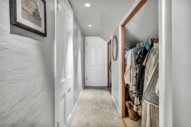 hall with light colored carpet and lofted ceiling