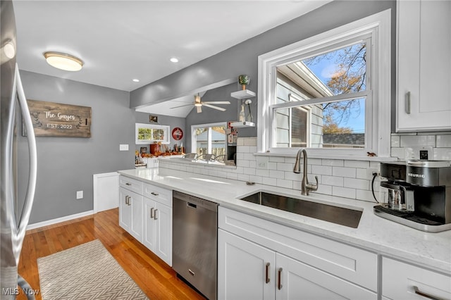 kitchen featuring stainless steel appliances, ceiling fan, sink, light hardwood / wood-style floors, and white cabinetry