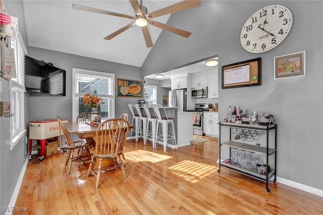 dining area featuring ceiling fan, light wood-type flooring, and high vaulted ceiling