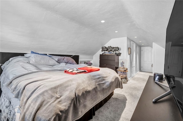 bedroom featuring a textured ceiling, light colored carpet, and lofted ceiling