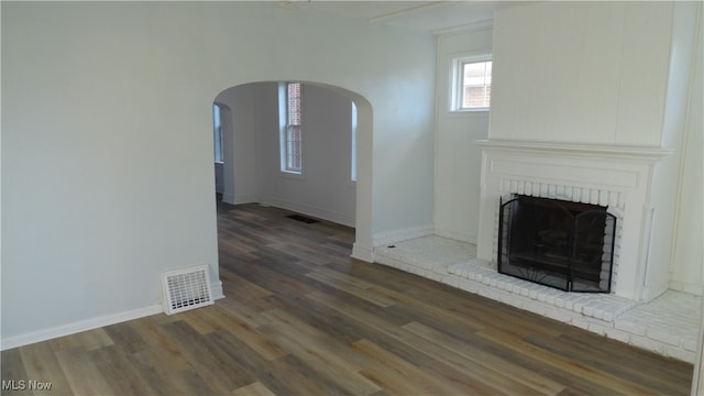 unfurnished living room with a brick fireplace and dark hardwood / wood-style flooring