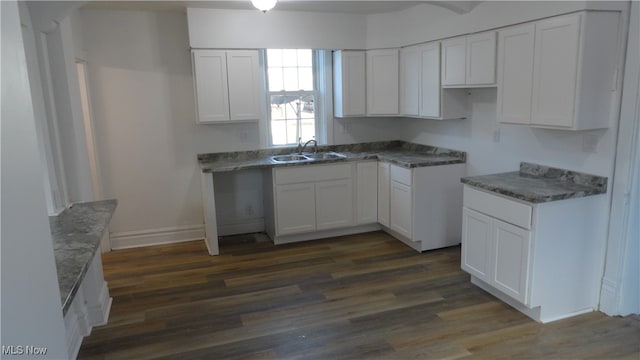 kitchen with white cabinets, dark wood-type flooring, sink, and stone counters