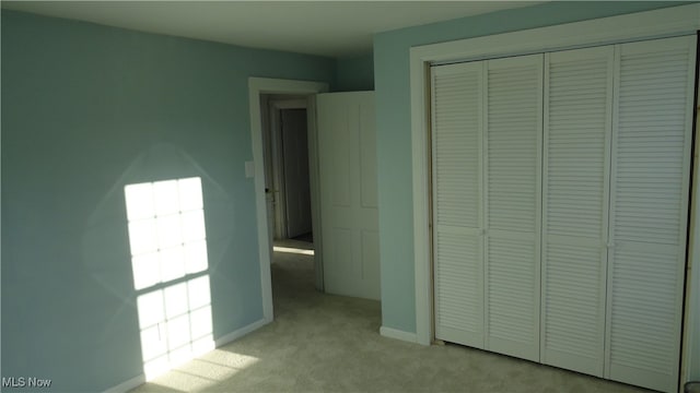 unfurnished bedroom with a closet and light colored carpet