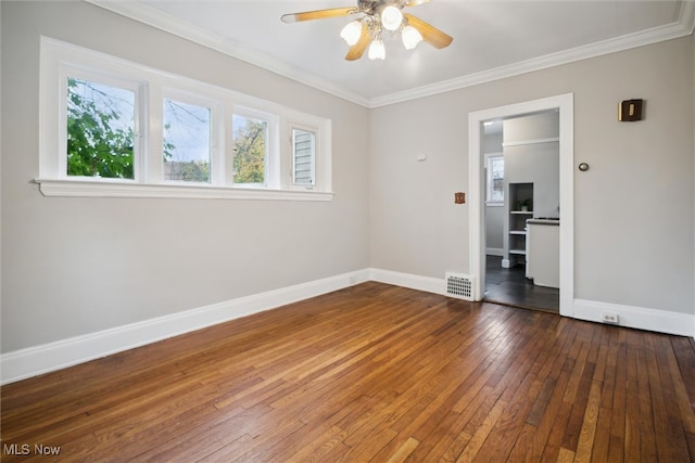 spare room featuring dark wood-type flooring, ceiling fan, and crown molding