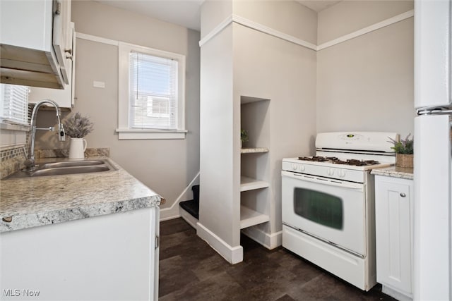 kitchen with white cabinets, white gas range, and sink