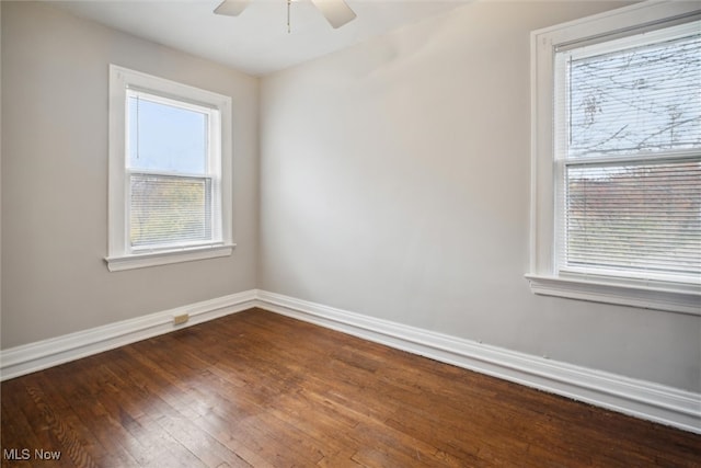 spare room with dark wood-type flooring, ceiling fan, and a healthy amount of sunlight