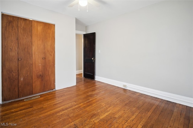 unfurnished bedroom with dark hardwood / wood-style flooring, a closet, and ceiling fan