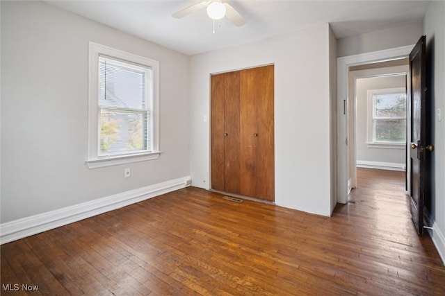 unfurnished bedroom featuring ceiling fan, a closet, and dark hardwood / wood-style flooring