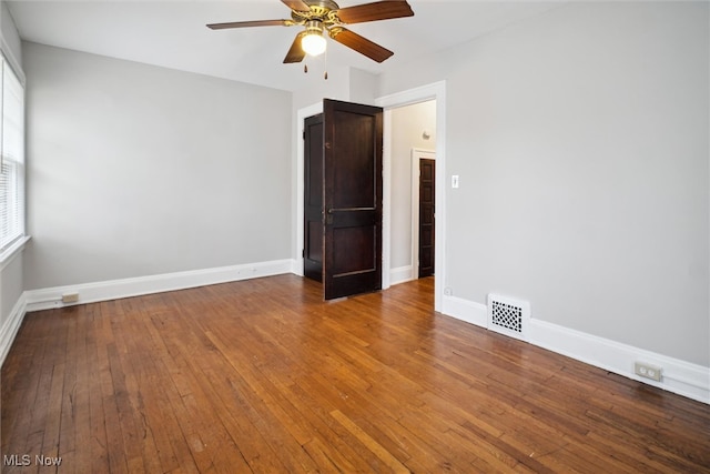 empty room featuring a wealth of natural light, hardwood / wood-style floors, and ceiling fan