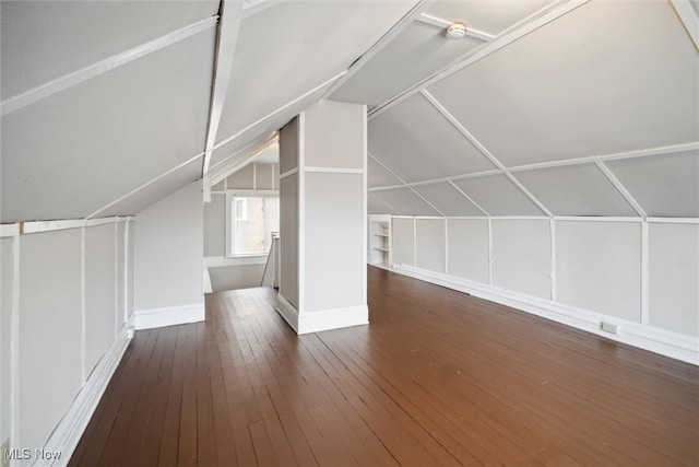 additional living space featuring dark wood-type flooring and lofted ceiling