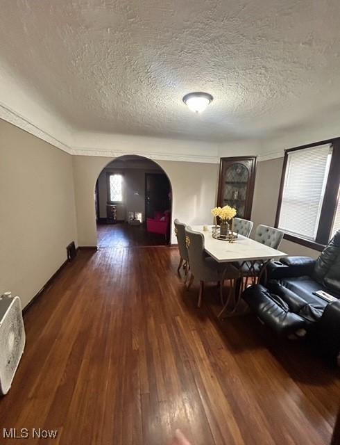 unfurnished dining area with a textured ceiling, ornamental molding, and dark wood-type flooring