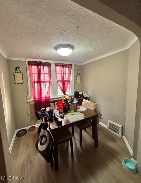 dining space with hardwood / wood-style floors and a textured ceiling