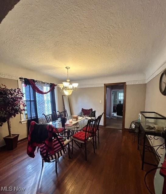 dining space with an inviting chandelier, a textured ceiling, and dark wood-type flooring