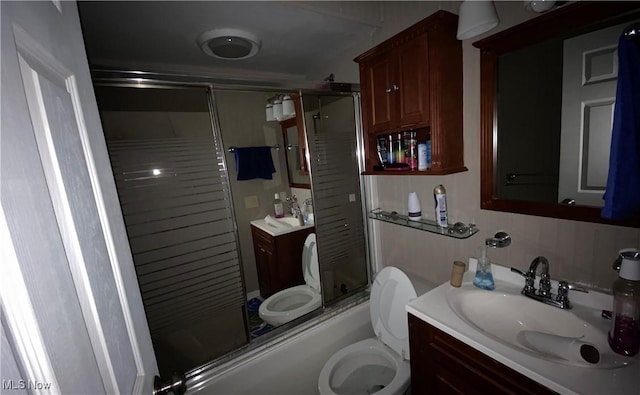 full bathroom featuring combined bath / shower with glass door, vanity, and toilet