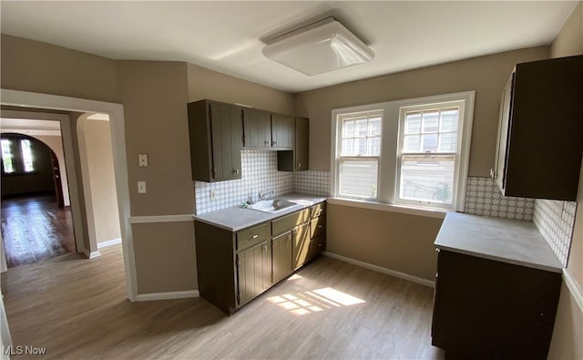 kitchen featuring decorative backsplash, light hardwood / wood-style flooring, dark brown cabinets, and sink