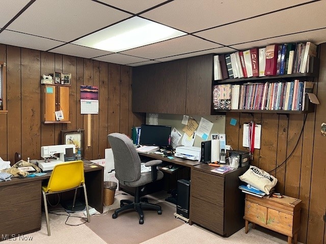 home office featuring wooden walls, a drop ceiling, and light carpet