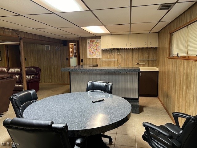 tiled dining room with bar area, a paneled ceiling, and wooden walls