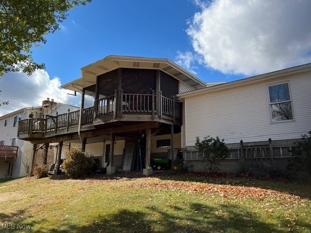 back of property with a sunroom, a wooden deck, and a yard