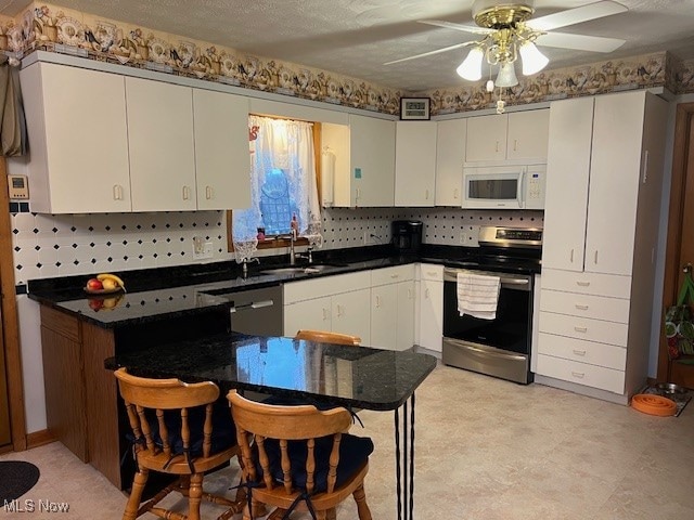 kitchen with backsplash, white cabinets, ceiling fan, and stainless steel appliances