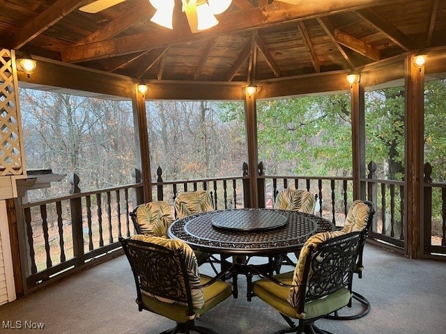 sunroom with vaulted ceiling with beams, a healthy amount of sunlight, and wooden ceiling