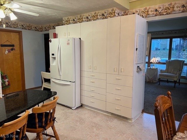 interior space featuring white cabinetry, white fridge with ice dispenser, a textured ceiling, and ceiling fan