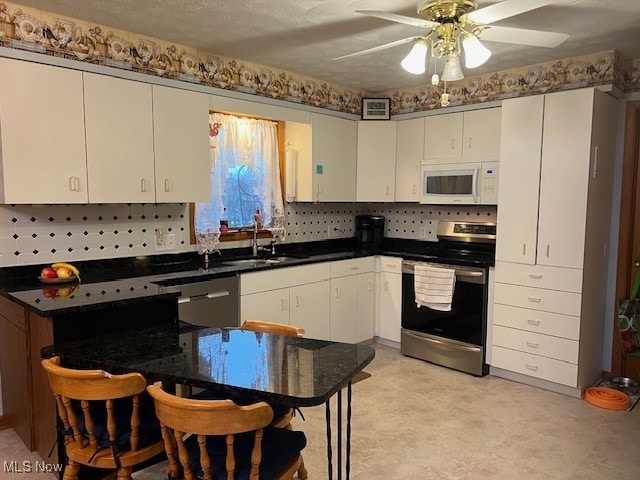 kitchen featuring stainless steel appliances, a kitchen bar, white cabinetry, and sink