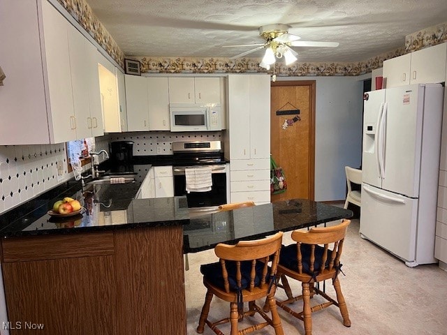 kitchen featuring sink, kitchen peninsula, ceiling fan, a textured ceiling, and white appliances